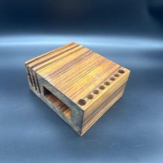 a small wooden box with holes in the middle on a blue background, it is made out of wood