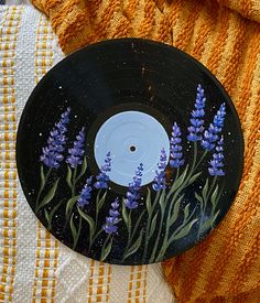 a record with flowers painted on it sitting next to a yellow and white blanket,