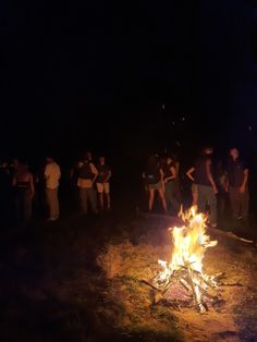 a group of people standing around a campfire