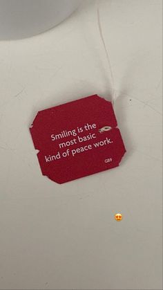 a piece of red paper that says, smiling is the most basic kind of peace work