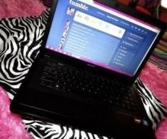 an open laptop computer sitting on top of a pink blanket