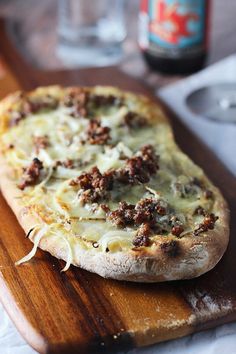 a pizza sitting on top of a wooden table covered in cheese and meat toppings