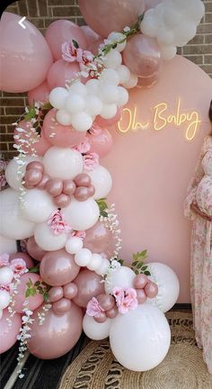 a pregnant woman standing next to balloons and flowers