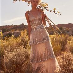 a woman is standing in the desert with flowers on her head and wearing a sequin dress