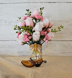 "Adorable country chic mini cowgirl boot arrangement in a resin cream floral boot with rhinestone accents. This mini arrangement features pink silk roses that fade to white, hot pink gypsophila accent flowers, and greenery bush stems. The perfect little gift for that special cowgirl in your life, or for accenting your western or southwestern decor. Dimensions for overall arrangement: 8-1/2\" High x 7\" Wide Dimensions for mini boot only: 4\" High x 4-1/2\" Wide" Boot Flower Arrangement, Cowboy Boot Vase With Flowers, Boot Floral Arrangement, Flowers In Boots, Cowgirl Boot Flower Vase, Boot Flower Vase, Pink Gypsophila, Accent Flowers, Floral Boots