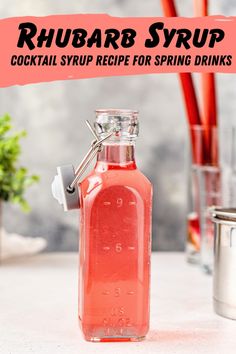 a bottle filled with pink liquid sitting on top of a table next to a cup