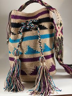 a crocheted bag with tassels on the handles