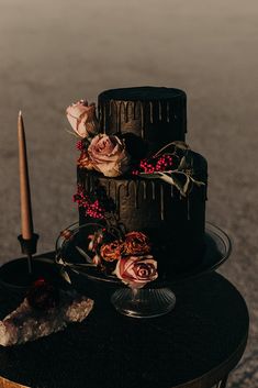 a three tiered cake sitting on top of a wooden table next to a candle