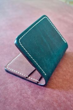 "This is a handmade compact bifold leather wallet from Second Line Leather out of New Orleans, LA.   The exterior is made from Pueblo Leather in Navy color from the Badalassi Carlo Tannery in Tuscany, Italy.  Pueblo is a full grain leather with a nice supple feel with a small amount of firmness. This leather has a unique rustic look that adds beautiful depth to the leather and makes for an amazing patina as it ages.   This wallet is lined on the inside so that no flesh side of the leather is showing giving the wallet a nice clean look.  The interior and lining are made with full grain vegetable tanned \"Graffiti\" leather in Bordeaux color from MPG Industria Conciaria in Italy.  Graffiti's signature characteristic is the sporadically scratched/swirled grain, which becomes subdued after han Handmade Bifold Card Holder, Handmade Green Leather Trifold Wallet, Handmade Bifold Card Holder For Daily Use, Handmade Trifold Card Holder, Bordeaux Color, Second Line, Tuscany Italy, Slim Wallet, Bifold Wallet