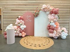 an arch with balloons and flowers on the top is set up in front of a wall