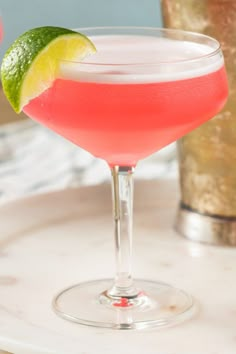 a close up of a drink in a glass with a lime slice on the rim