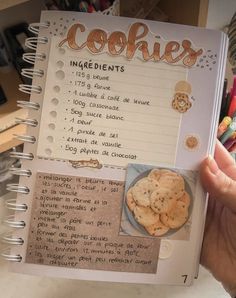 someone holding up a recipe book with cookies on it