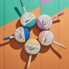 four different colored pots and pans sitting on top of a wooden floor next to each other