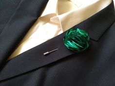 a close up of a tie and lapel pin on a suit jacket with a green flower