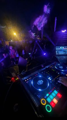 a dj mixing in front of a laptop computer at a party with fireworks and palm trees