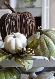 pumpkins and gourds are sitting on a table in front of a wicker basket