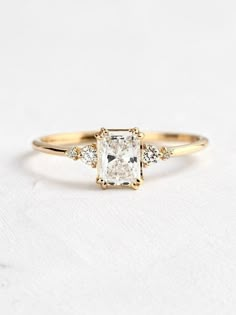 an engagement ring with a princess cut diamond in the center and three small diamonds on each side