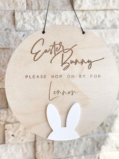 a wooden sign hanging from the side of a brick wall that says, easter bunny please hop on by for lemon