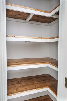 an empty pantry with white shelves and wood flooring on the bottom half of each shelf