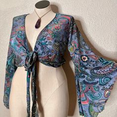 Brand New, Without Tags, Silk Like Fabric, Beautiful Paisley Print. Very Boho Vibes, Free Spirit Gypsy Shirt, Semi Crop Fit, Wrap Around Top. Can Also Be Worn Tied At The Front For A More Revealing Style. Features Long Sleeves With Bell Sleeves Detail. Measurements Laying Flat: Shoulder To Bottom 18”, Waist 15” (Approximate Measurements). Size Listed States L, However It Is A One Size, And There Is No Tag, Please See Measurements Listed Above Instead. Sewing Bell Sleeve Top, Bell Sleeve Top 70s, Boho Wrap Top, Blue Hippie V-neck Top, Fitted V-neck Top For Beach Cover-up, Casual Wrap Crop Top For The Beach, Multicolor Wrap Tops For Vacation, Spring Beach Wrap Crop Top, Bohemian Stretch Top For Beach Cover-up