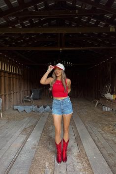 a woman in red shirt and cowboy hat standing on wooden floor next to barn door