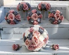 a bouquet of pink and grey flowers sitting on top of a white bench next to other fake flowers