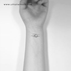 a small wrist tattoo with an eye on the left side of the arm, in black and white