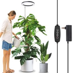 a woman standing next to a potted plant and an electronic device connected to it