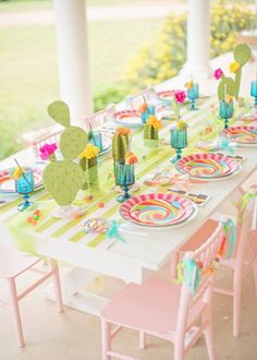 a table set up with colorful plates and cactus decorations