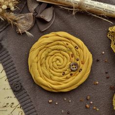 a yellow flower sitting on top of a table next to some thread and buttons,