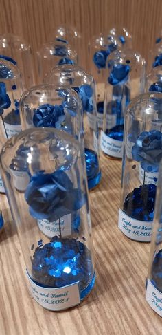 many blue flowers are in glass cases on a wooden table with labels for each one