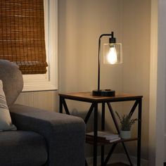 a living room with a couch, table and lamp on the side by the window