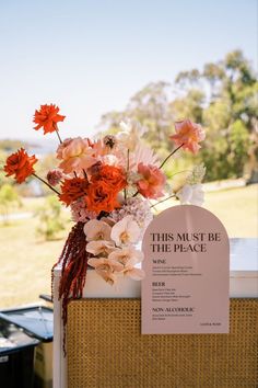 a vase filled with flowers sitting on top of a wooden table next to a sign