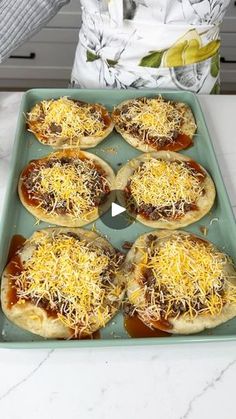 six homemade pizzas with cheese and sauce on a baking sheet ready to go into the oven