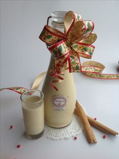 two cinnamon sticks are next to a bottle with a bow on it and a glass filled with milk