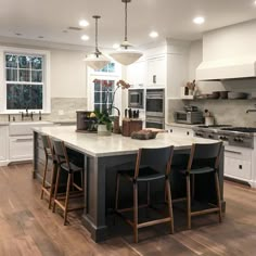 a large kitchen with an island in the middle and two chairs at the counter top