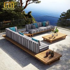 an outdoor living area with couches, tables and coffee table on the patio overlooking the water