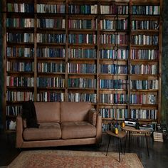 a couch and table in front of a bookcase with many books on the shelves