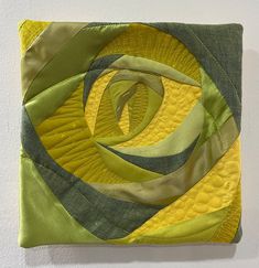 a green and yellow piece of art hanging on a wall