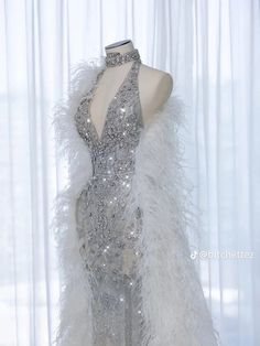 a white dress with silver sequins and feathers on display in front of a window