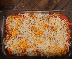 a casserole dish with cheese and sauce in it sitting on a wooden table