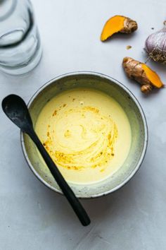 a bowl filled with yellow liquid next to some garlic