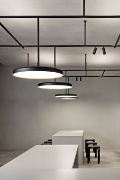 an empty room with several tables and stools in it, all lit up by round lights