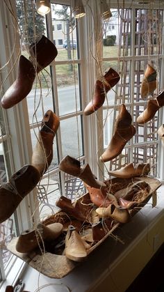 many pairs of shoes are hanging from the ceiling in front of a window with glass panes