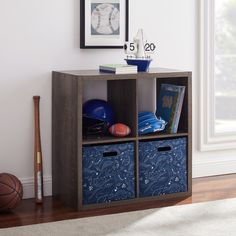 a book shelf with two baskets and a baseball bat on the floor next to it