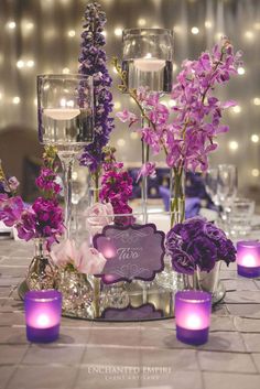 purple flowers in vases and candles on a table