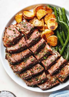 steak, potatoes and green beans on a white plate