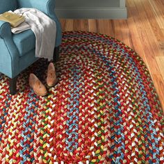 a blue chair sitting on top of a wooden floor next to a red and green rug