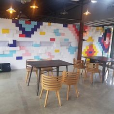 an empty room with tables and chairs in front of a wall that has colorful squares on it