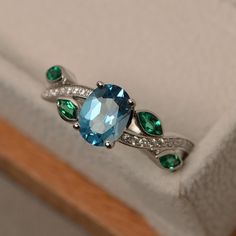 This ring features a 6*8mm oval cut Swiss blue topaz and marquise cut lab emerald. Customization is available. It is made by hand, and it will take about 7 days to finish the ring after your payment is completed. Main stone: Swiss blue topaz Main stone weight: Approx 1.40 ct Metal type: sterling silver finished with rhodium Accent stone: lab emerald and cz Customization is available, I also can make it with 14k solid gold (white or yellow or rose) and diamond accent stone, just feel free to ... Blue Topaz Ring Sterling Silver, Original Engagement Rings, Blue Gemstone Ring, Swiss Blue Topaz Ring, Blue Gemstone Rings, Blue Sparkles, Leaf Ring, Ring Oval, Swiss Blue Topaz